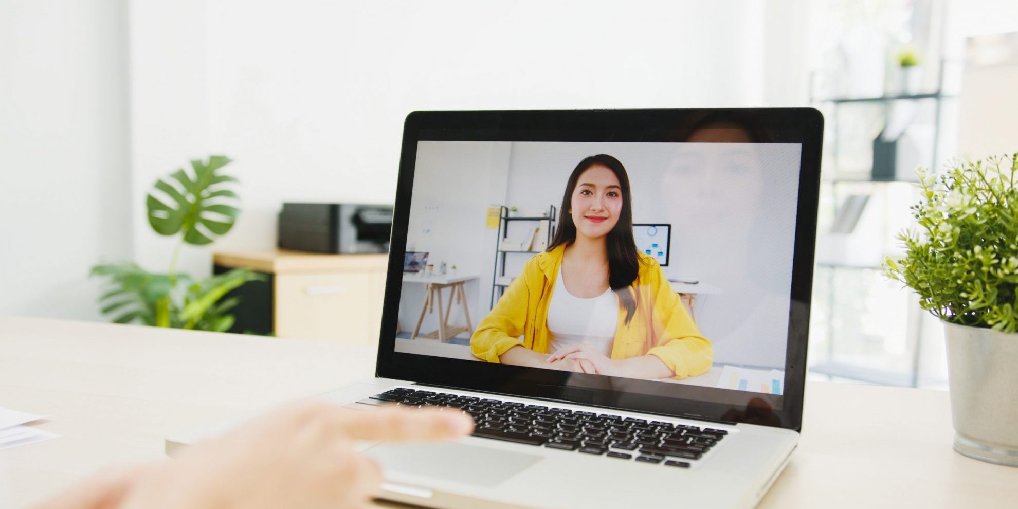 Photo of woman smiling on computer screen illustrates blog: "15 Questions You Should Ask When Hiring for a Remote Position"