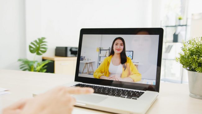 Photo of woman smiling on computer screen illustrates blog: "15 Questions You Should Ask When Hiring for a Remote Position"