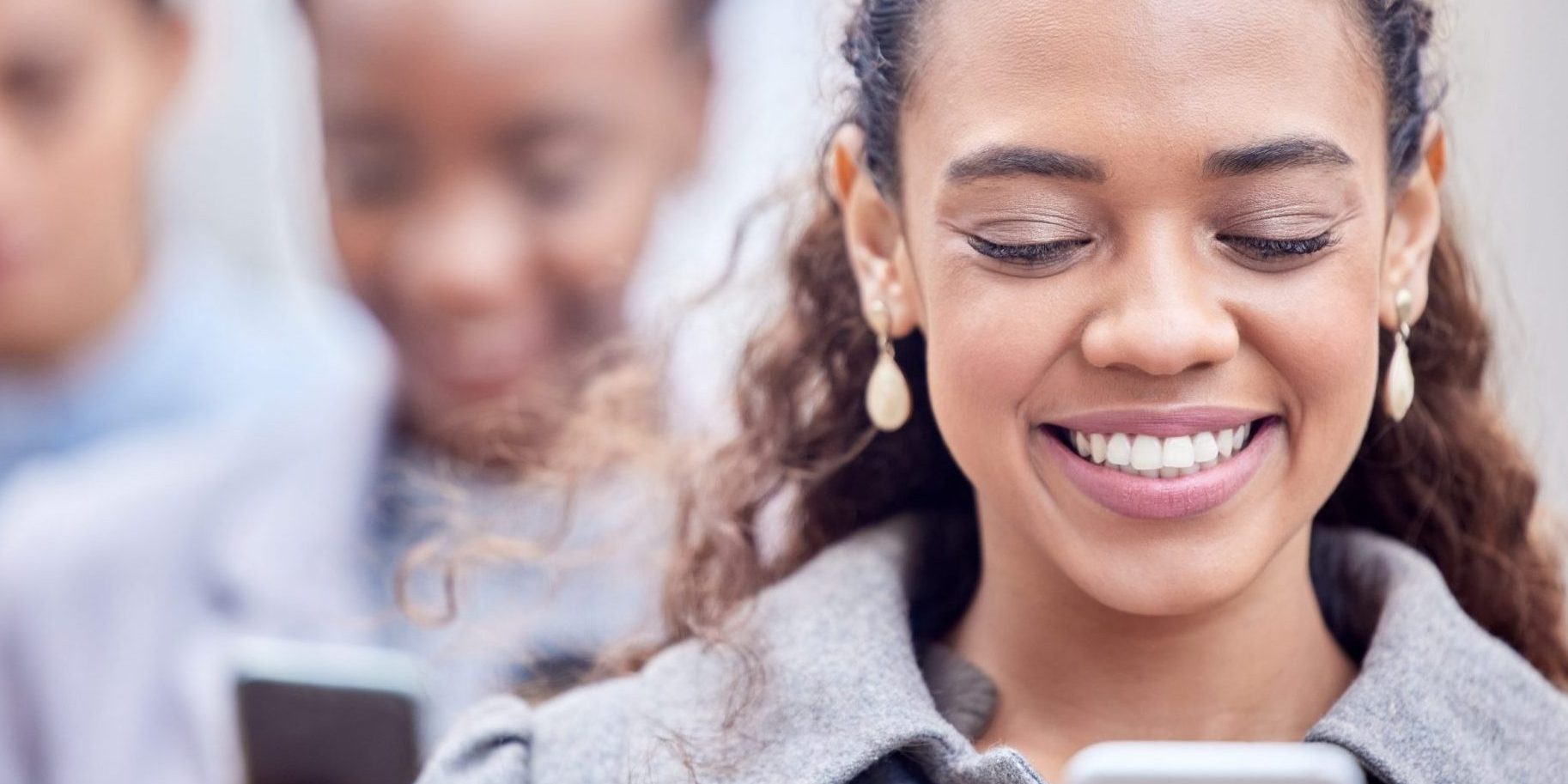 Photo of woman smiling looking at her smartphone illustrates blog: "What Is Candidate Experience and Why Is It Important?"
