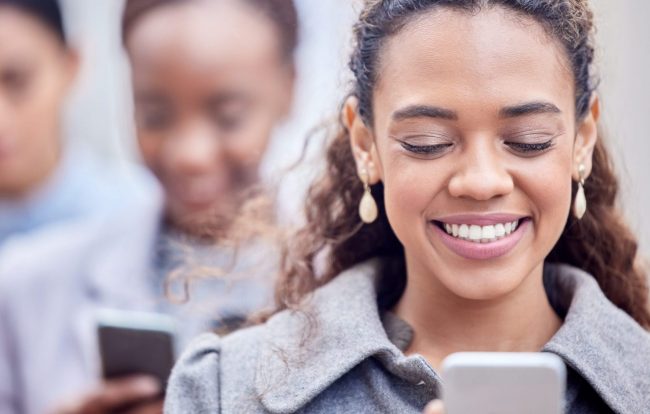 Photo of woman smiling looking at her smartphone illustrates blog: "What Is Candidate Experience and Why Is It Important?"