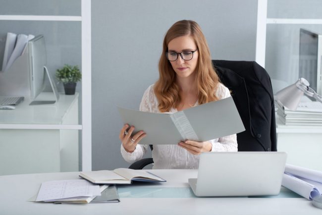 Woman looking at open folder illustrates blog "Are Background Checks Public Record?"