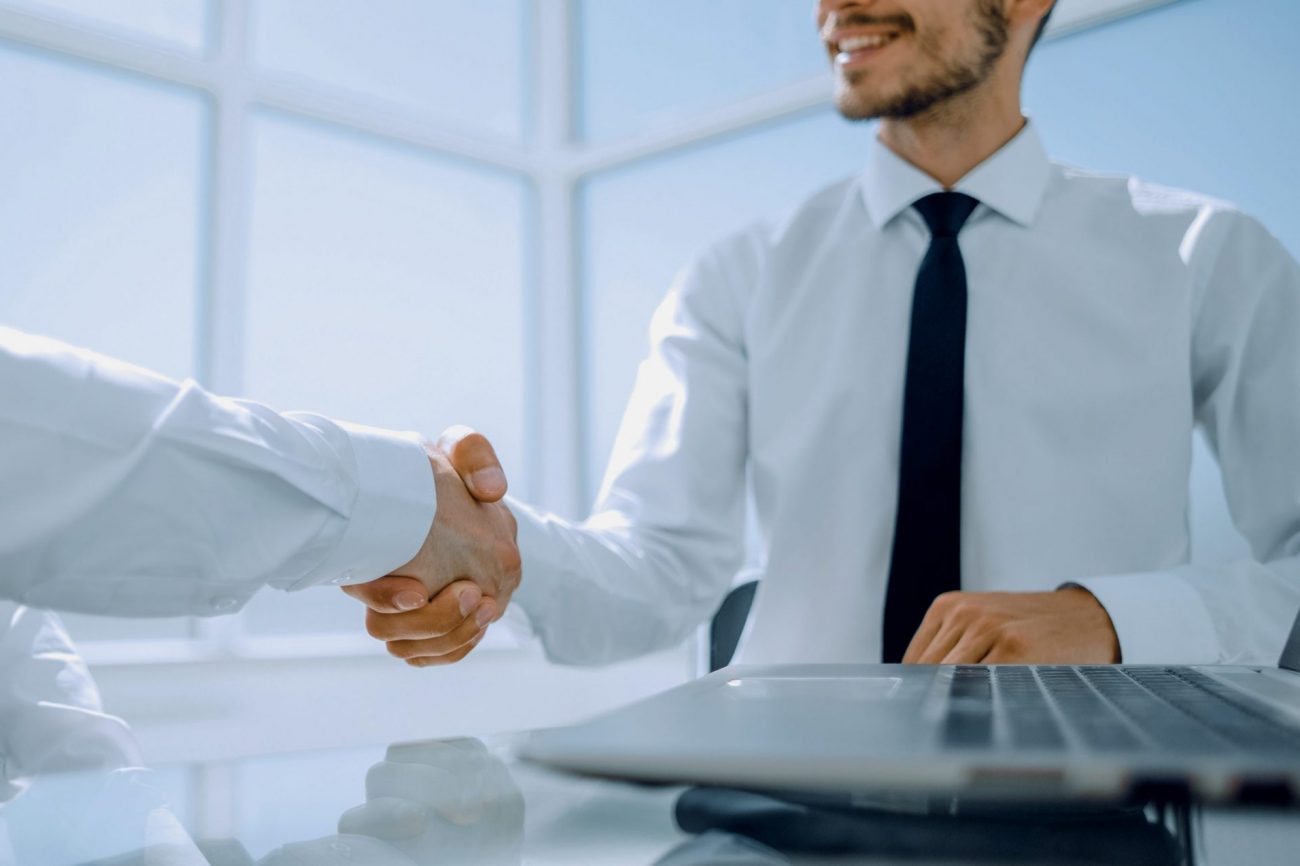 Two men shaking hands illustrate blog "Background Check vs Consumer Report: What Is the Difference?"