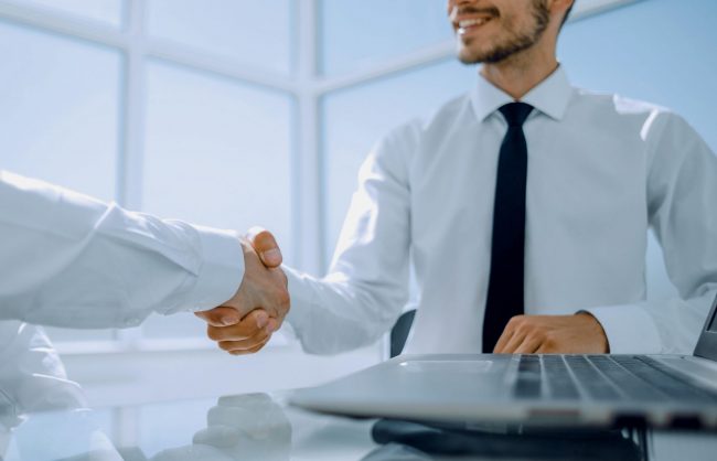 Two men shaking hands illustrate blog "Background Check vs Consumer Report: What Is the Difference?"