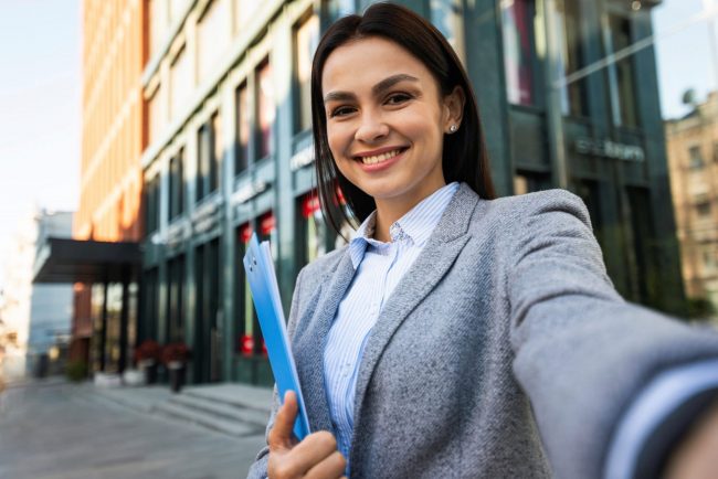 Smiling woman holding clipboard illustrates blog "5 Tips to Conduct Better Job Interviews"