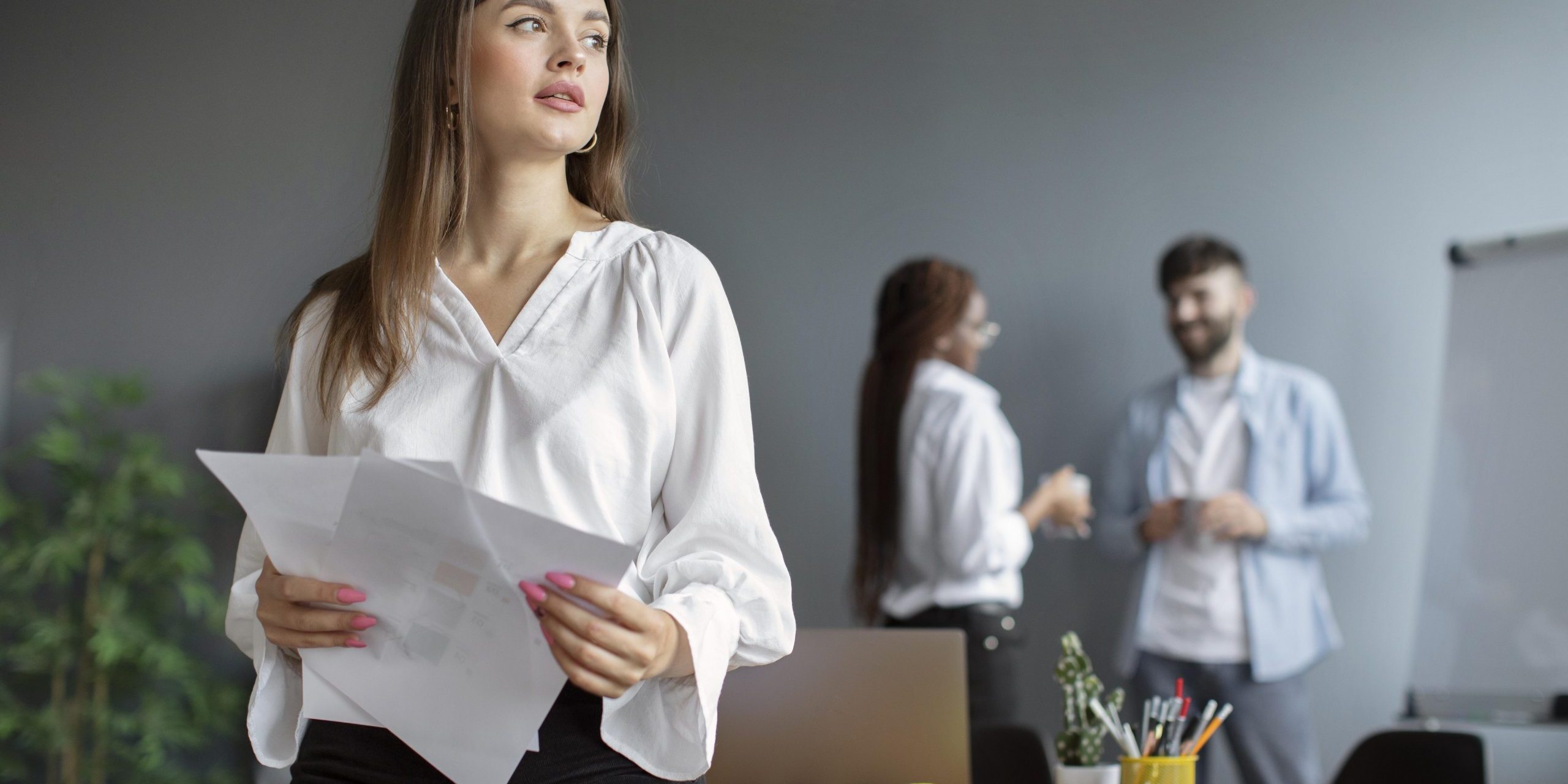 office-woman-fp Woman in office with man and woman in the background illustrates blog "What Is Performance Management?"