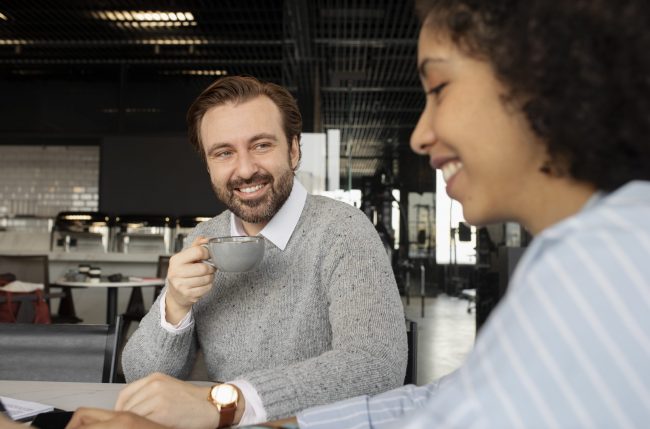 coworkers-FP Two coworkers drinking coffee during break illustrate blog "Why Is Recruiting Everyone's Job?"