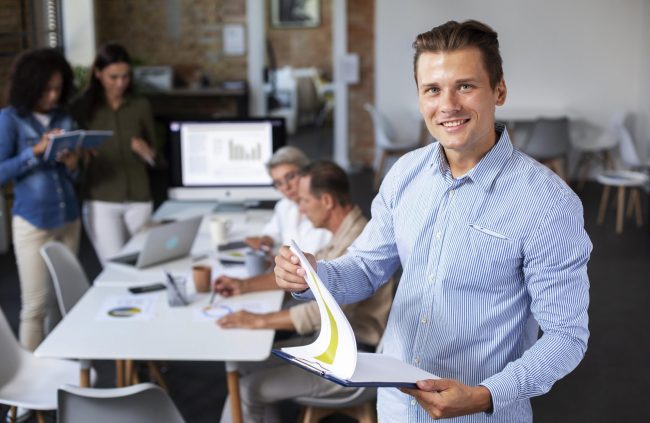 employee-office-fp Man in office holding clipboard illustrates blog "Internal Gigs and Background Screening"