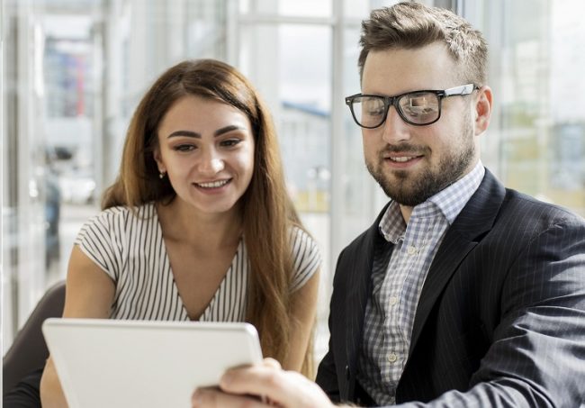 woman-man-tablet Woman and man looking at tablet illustrate blog "Background check vs Reference Check: "What Is the Difference?"