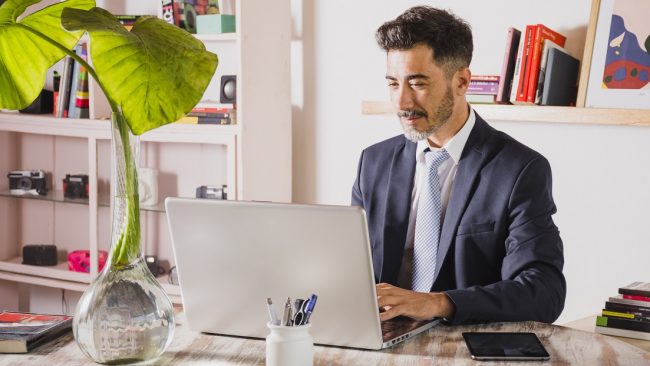 man-office-laptop-freepik Man in office typing on laptop illustrates blog "5 Background Screening Trends You Need To Know"